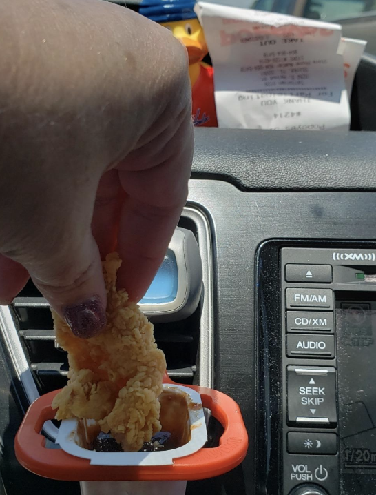 Reviewer dunking a nugget into some sauce in the sauce holder