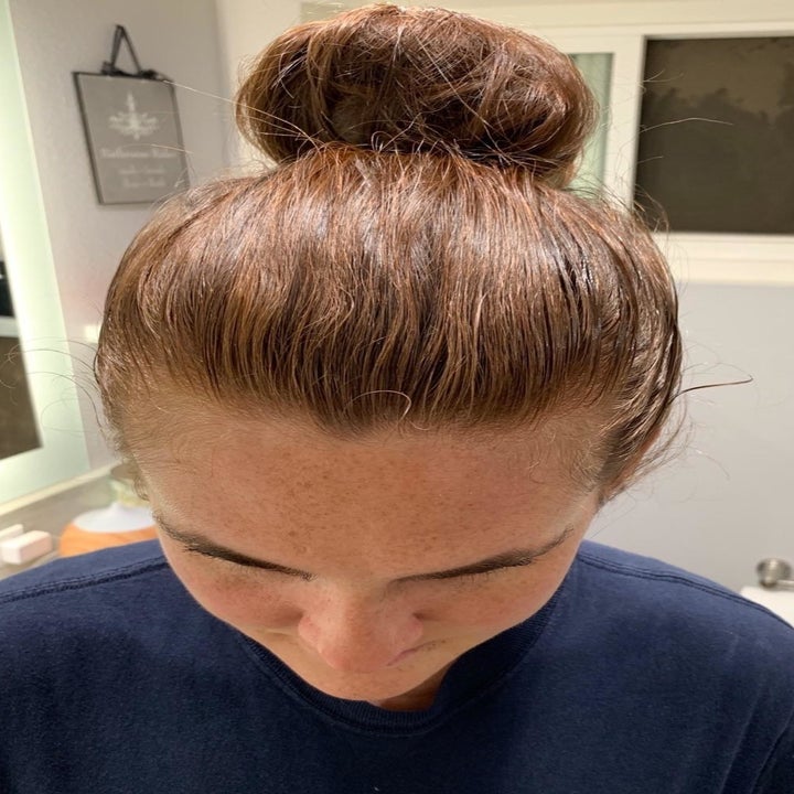 The same person showing their neater, slicked-back bun after using the hair-finishing stick