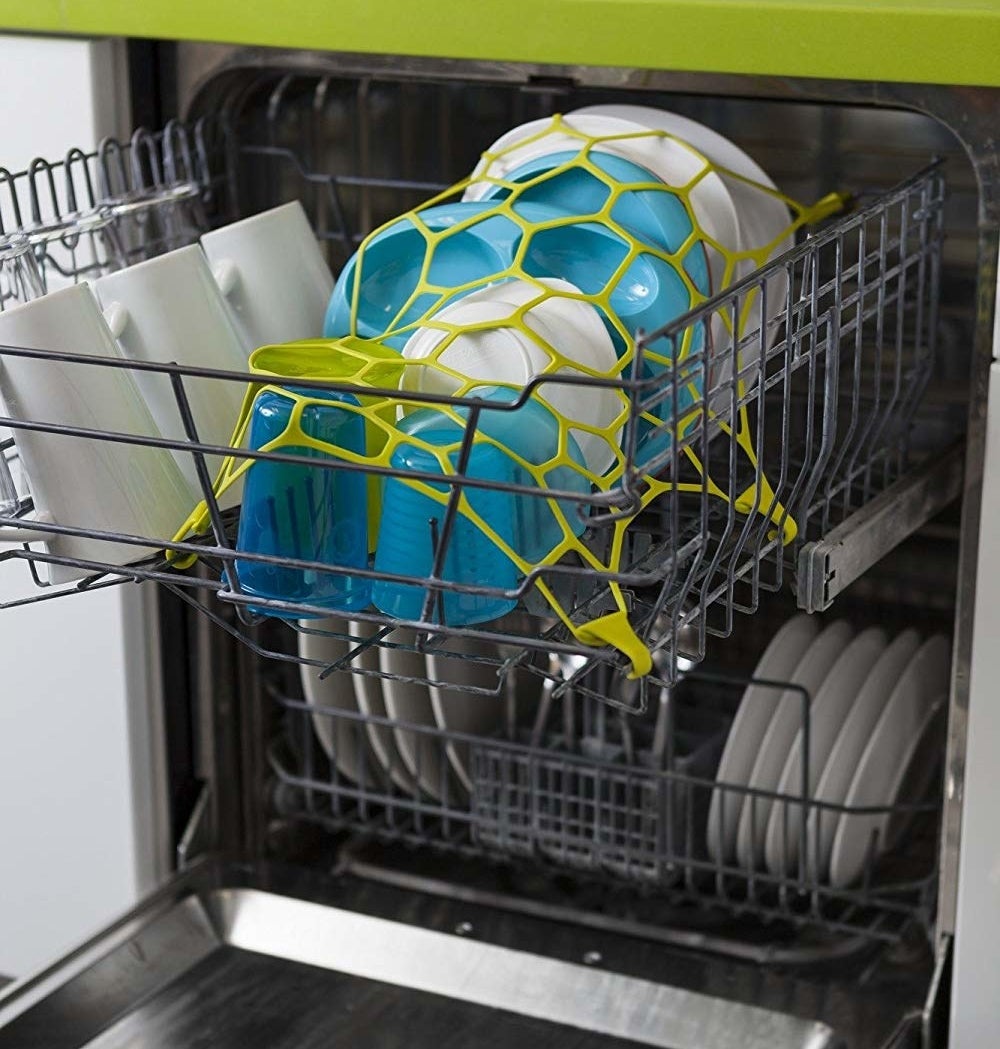 open washing machine with stretchy net on top of things in the top rack of dishwasher