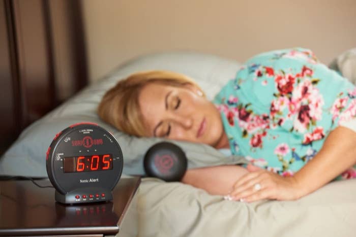 a woman sleeping near an alarm clock