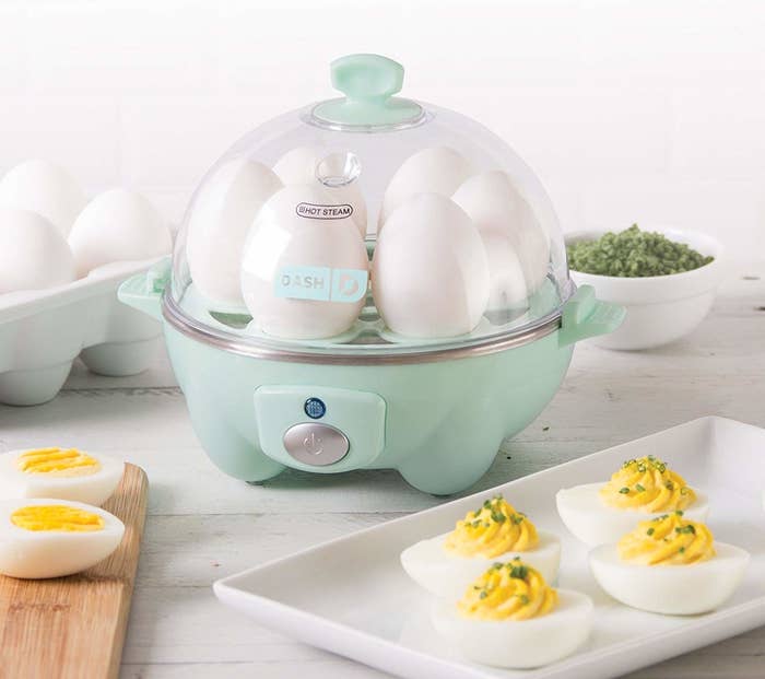 an electric egg cooker filled with eggs next to a plate of deviled eggs