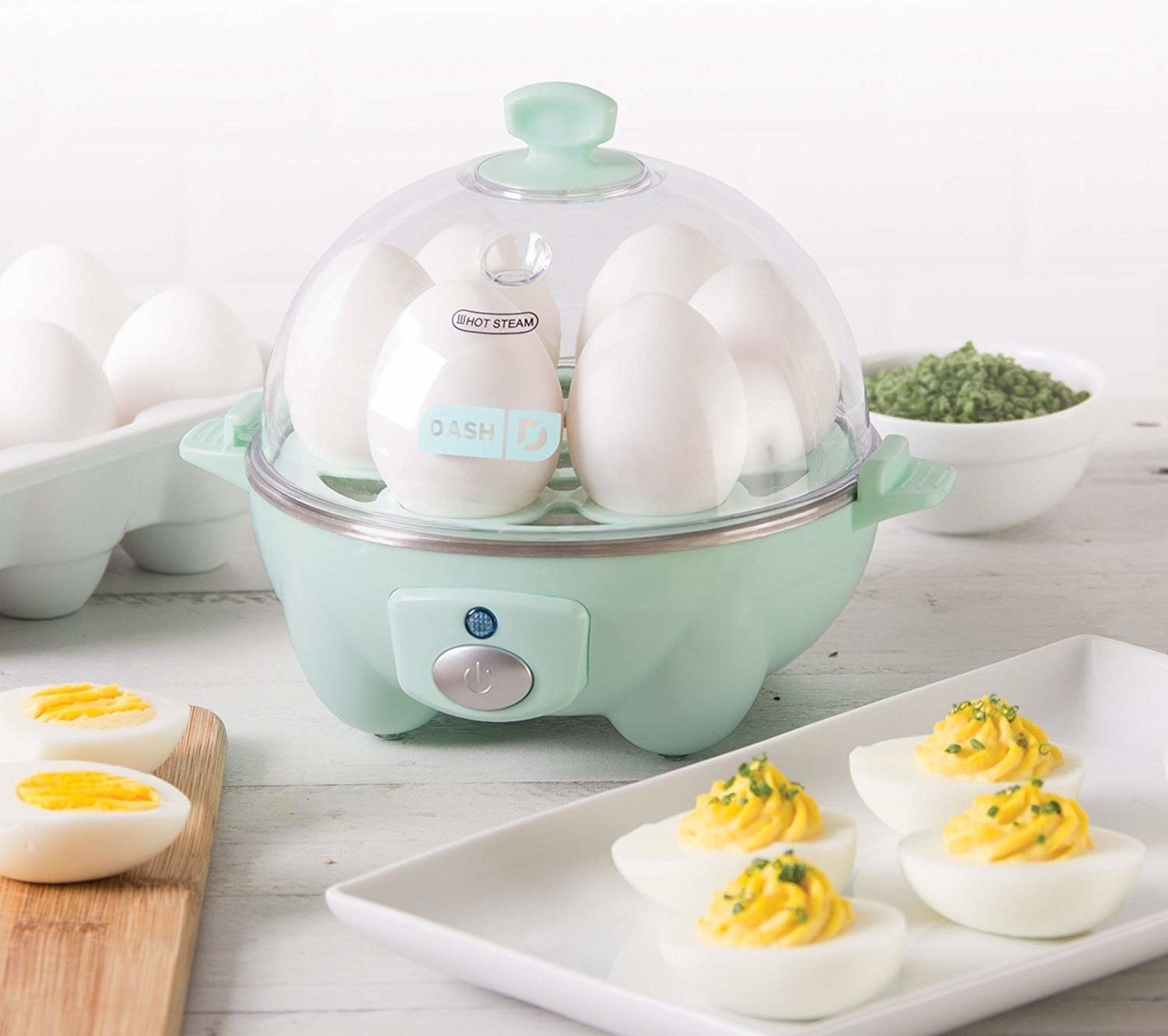 Dash rapid egg cooker placed on counter with deviled eggs on plate