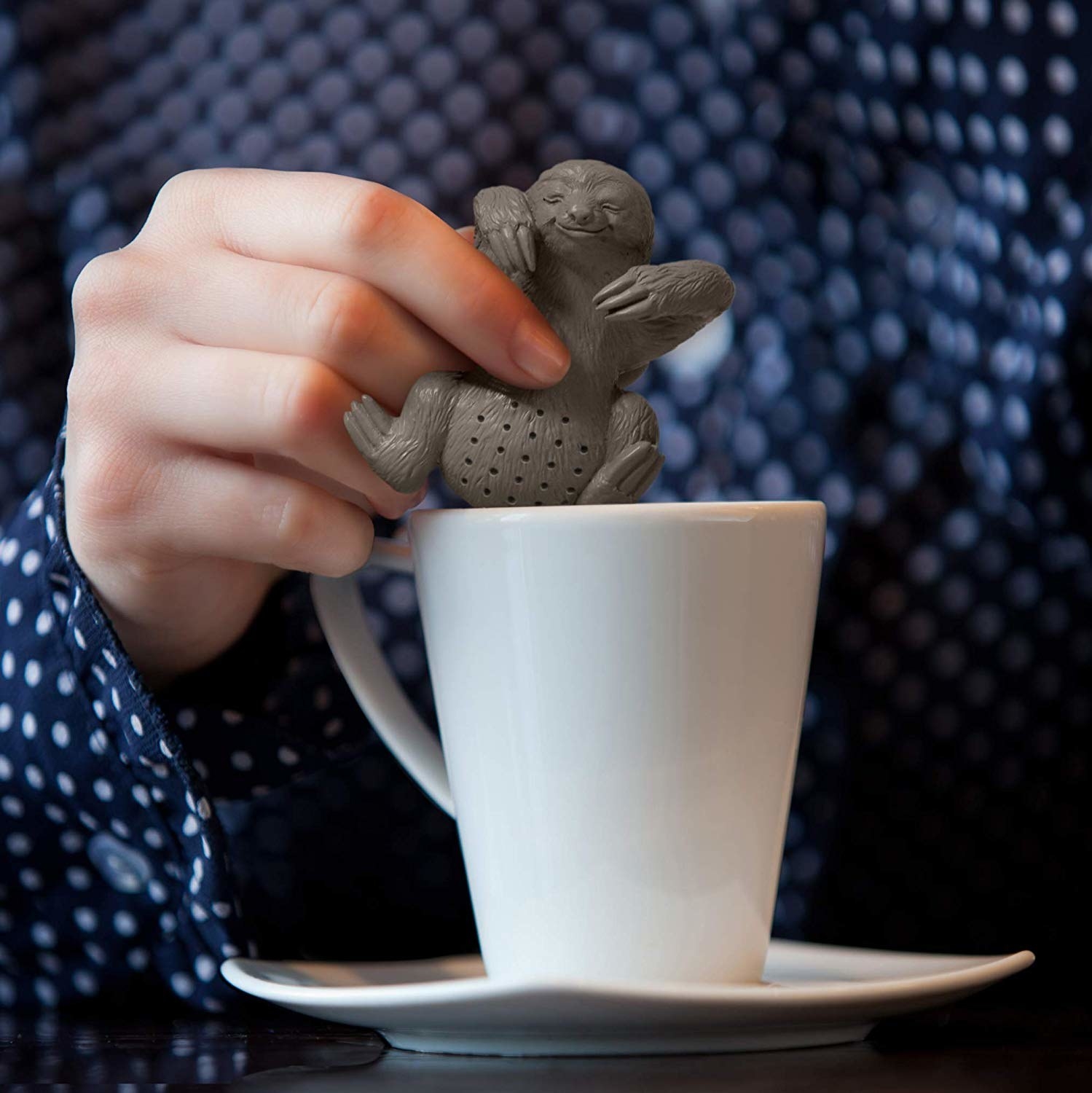 A person dipping the sloth infuser into a mug of tea