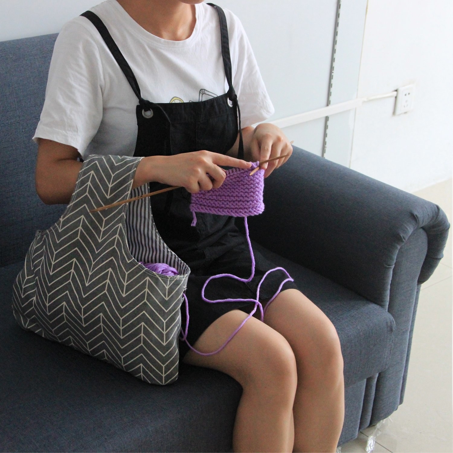 A person knitting with the bag next to them