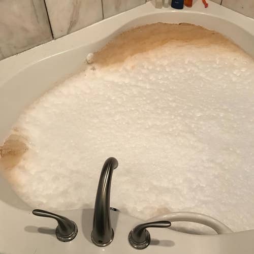 Reviewer's tub filled with dirty brown water that's been cleaned out of the jets
