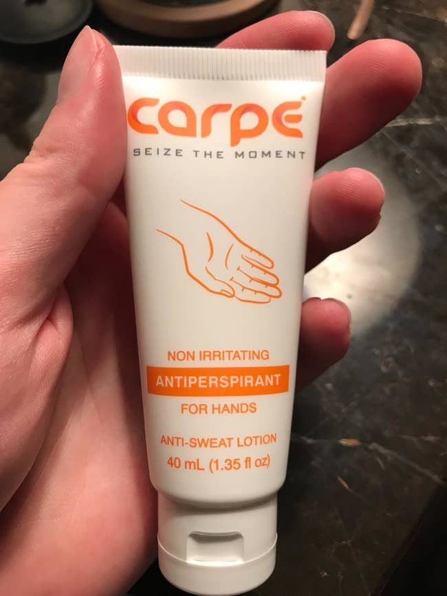 A reviewer holding a tube of lotion 