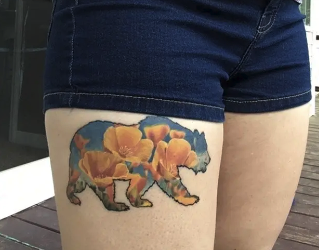 A thigh tattoo of a bear with flowers