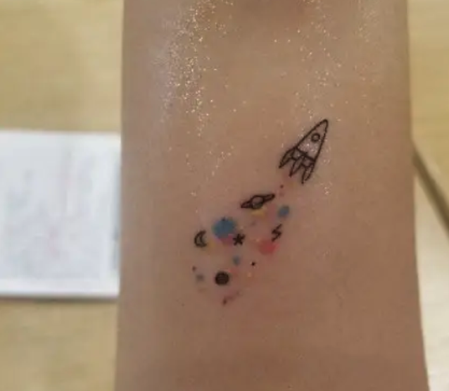 Rocket ship tattoo with colorful planets and stars