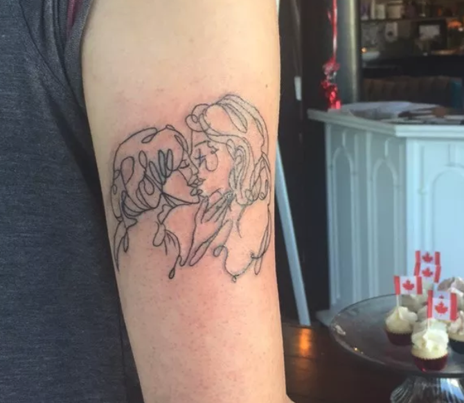 An arm tattoo of two women kissing