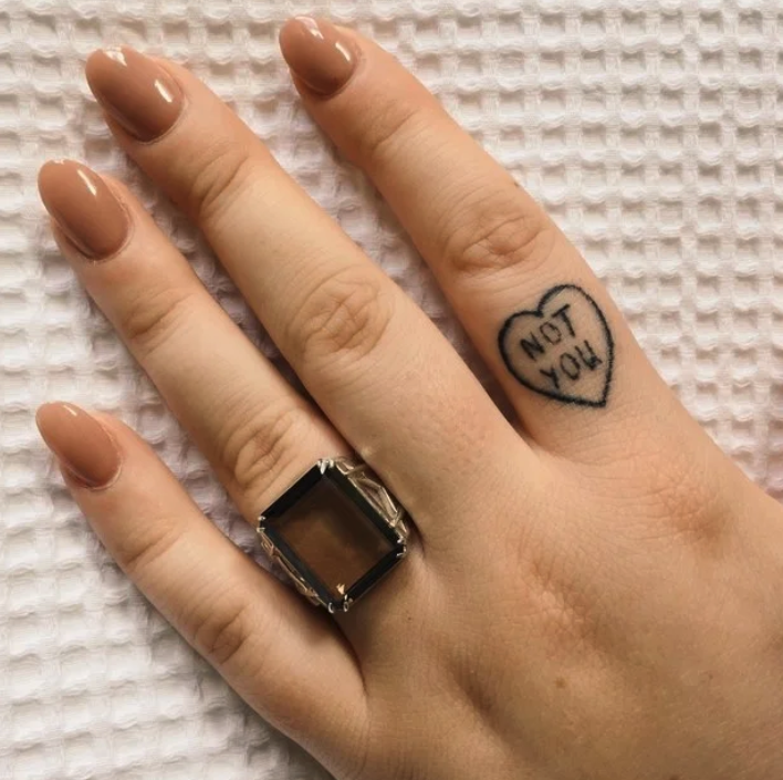 A finger tattoo of the words "not you" inside a heart