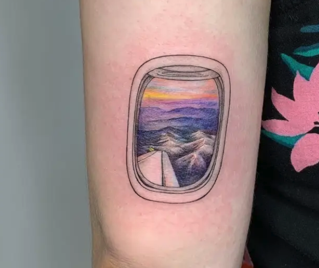 A colorful tattoo of the view from an airplane window on someone&#x27;s arm