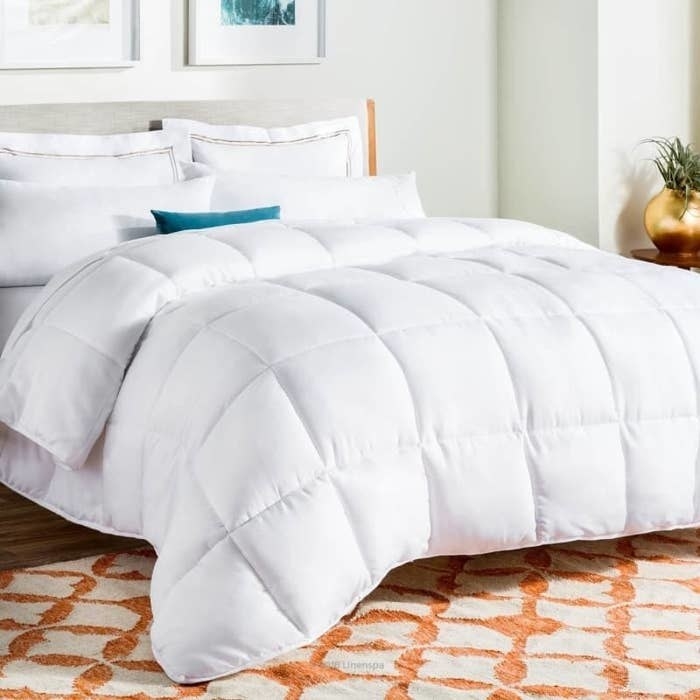 The comforter in white on top of a bed