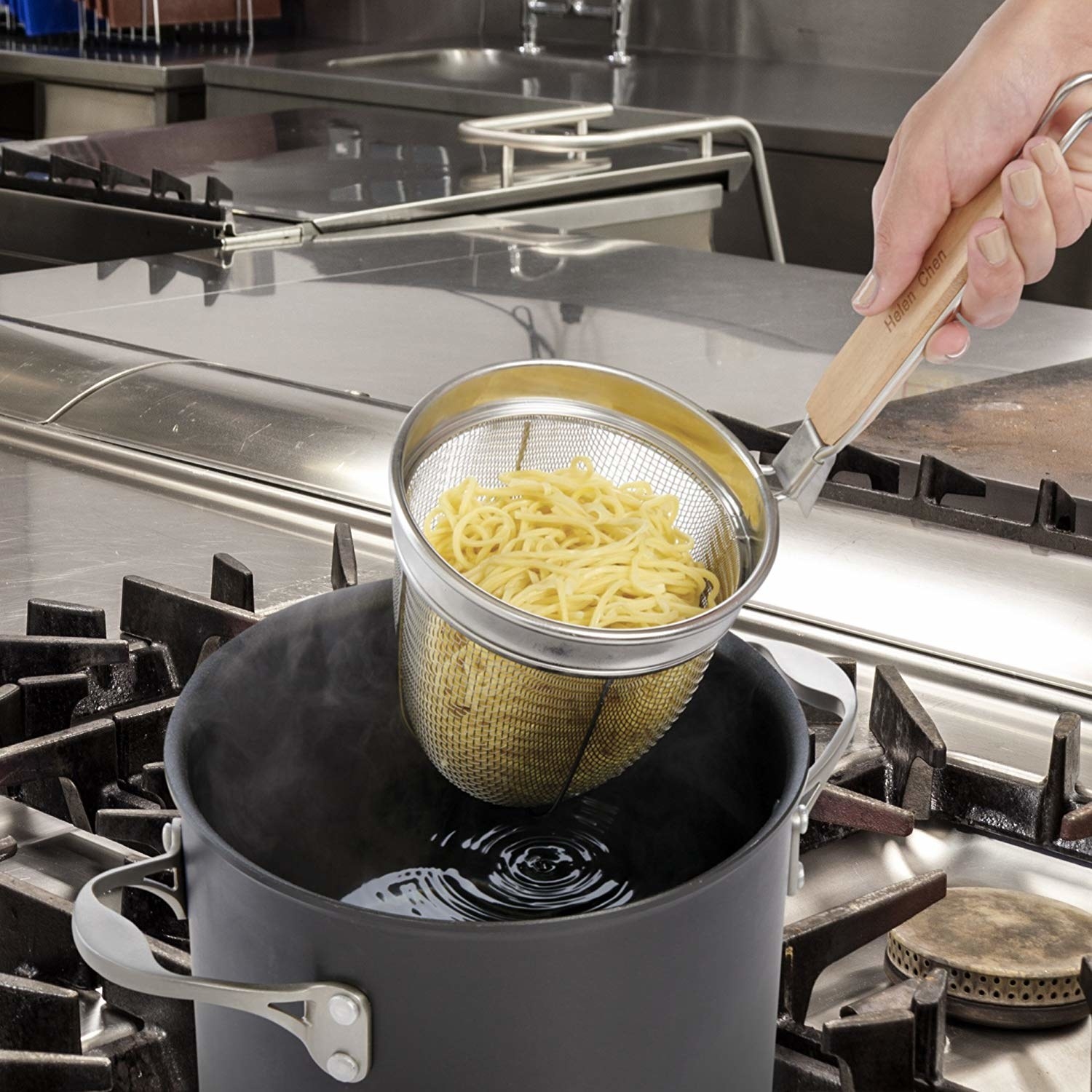 A person using the strainer to scoop up pasta