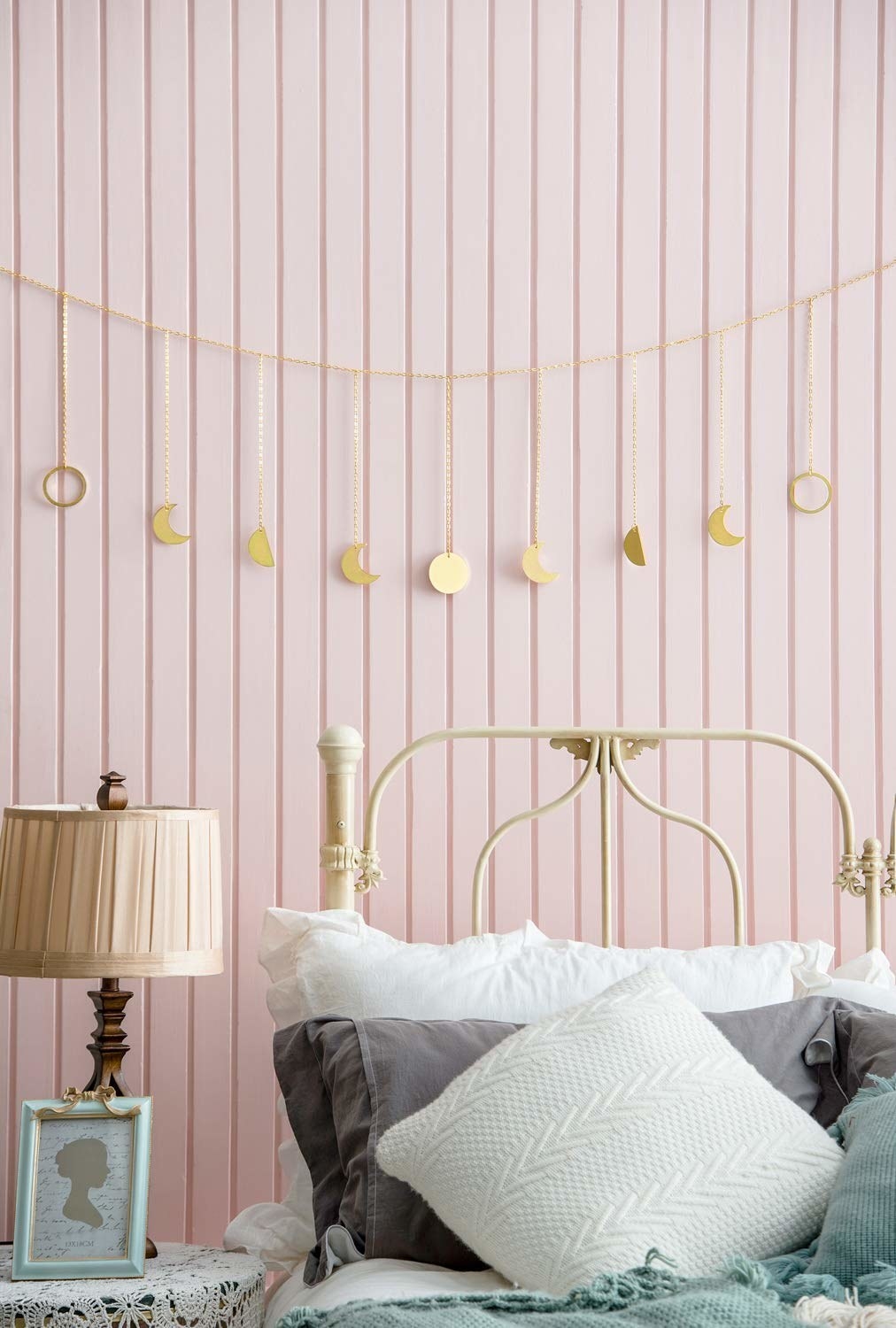 a string of garland over a headboard with moon phase charms hanging from it