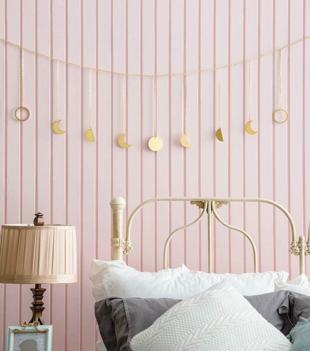 Gold garland with different shaped moons across hanging above a bed