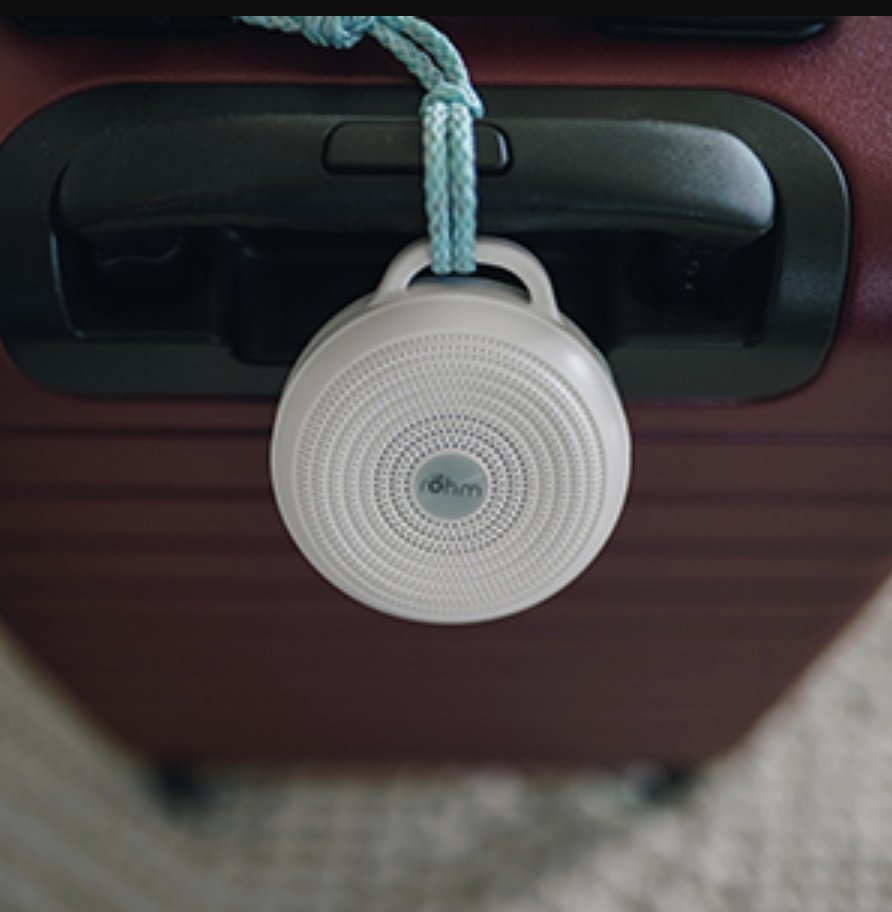 the small circular noise machine attached to the handle of a suitcase