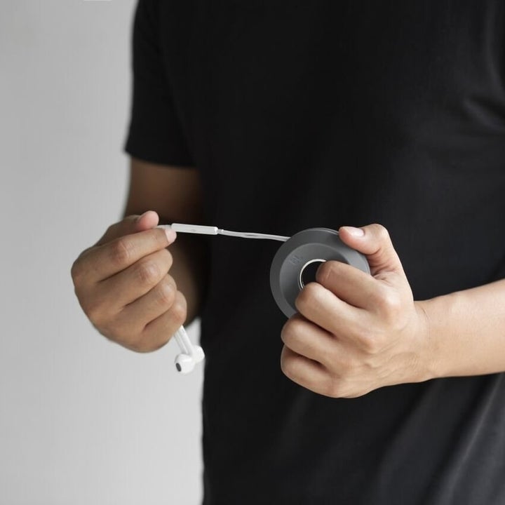 A person pulling their headphones out the cable spool