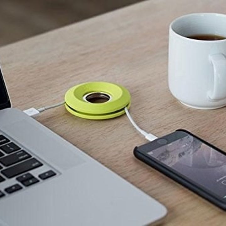 A phone with its cord running through the cable spool into a laptop