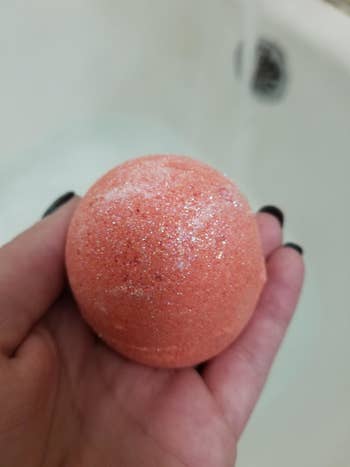 reviewer holding a coral bath bomb 