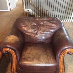 A brown leather armchair looking faded and worn