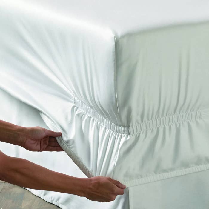 hands pull down fitted sheet with deep pockets