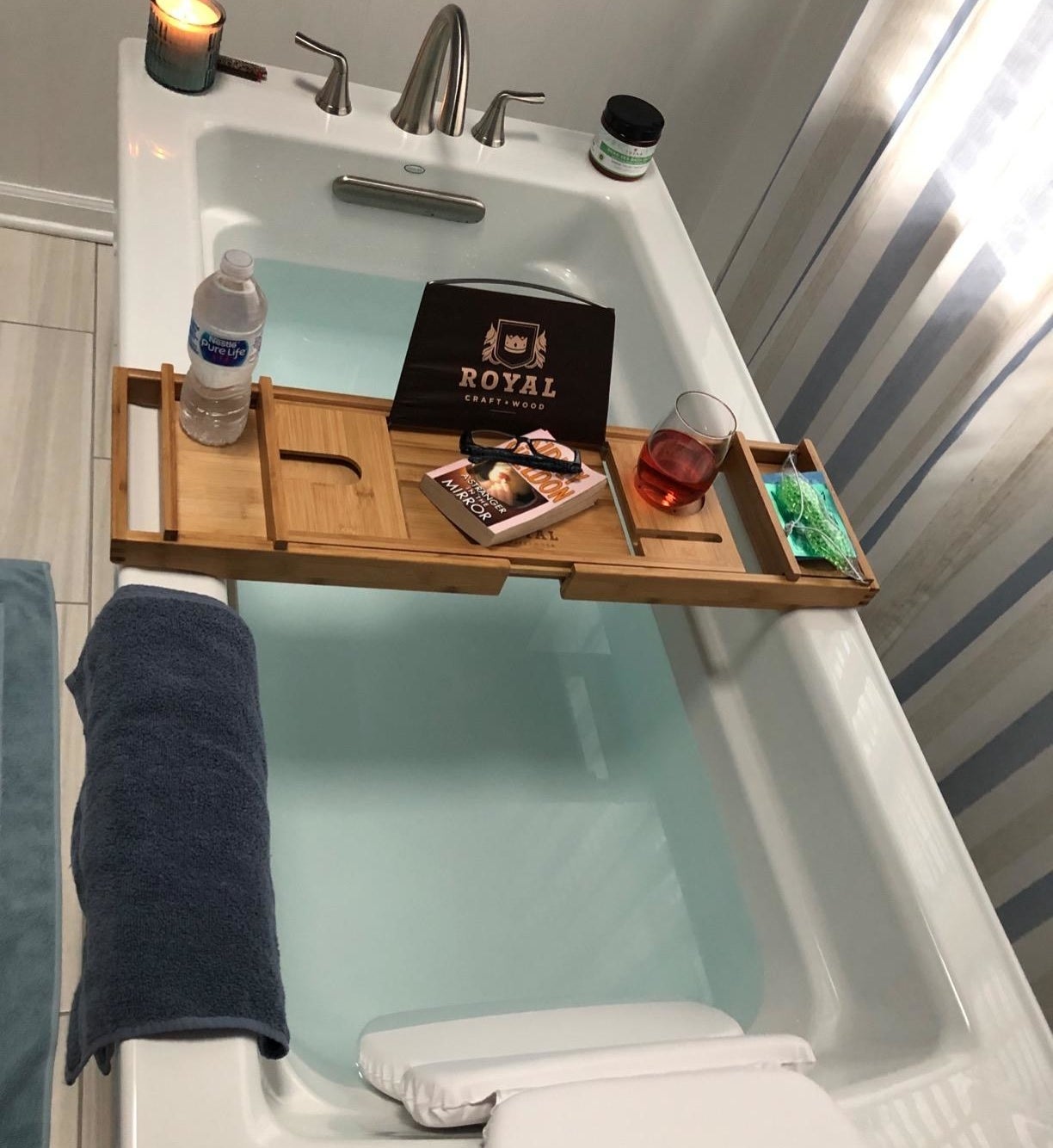 reviewer&#x27;s tub with bamboo tray across it holding a book and other accessories