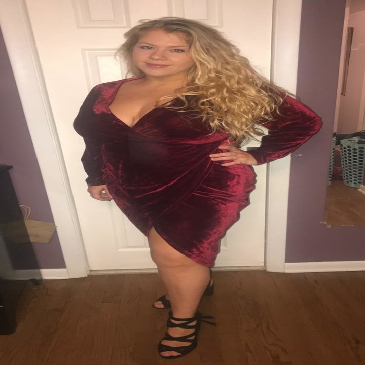 Reviewer wearing the wrap-style dress with a deep v-neck in red velvet