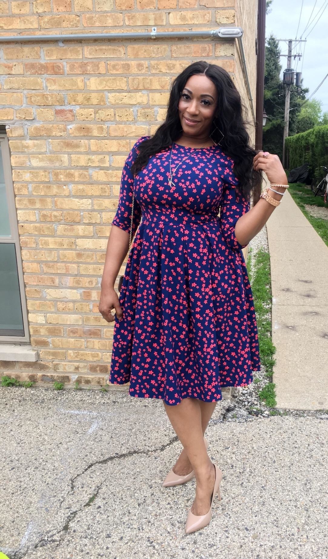 Reviewer wearing the knee-length dress in blue with small red flowers on it