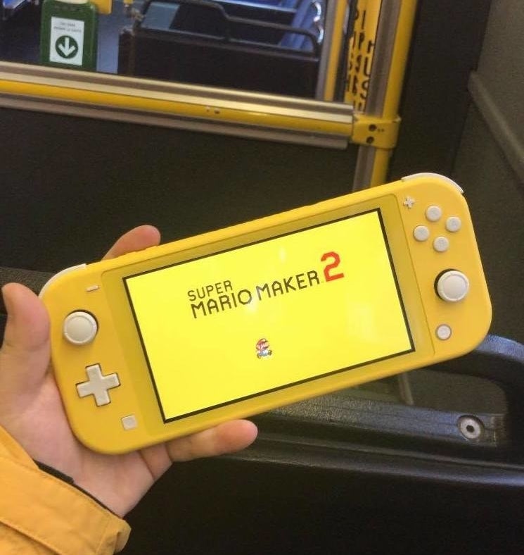 A person&#x27;s hand holding a Nintendo Switch Lite console