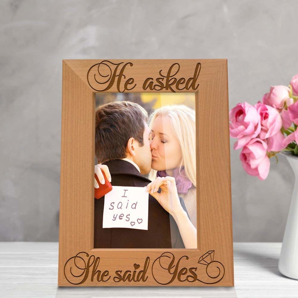 Wooden frame with the signature phrase &quot;he asked, she said yes&quot; etched into the bottom. 