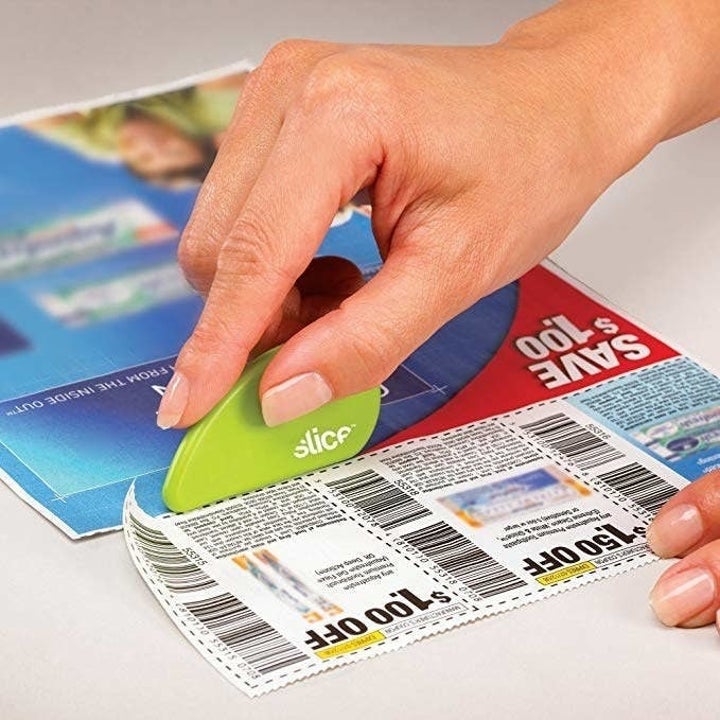 person using cutter to cut coupons