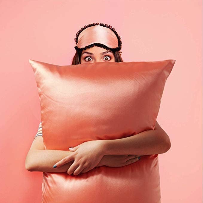 Model holding a pillow in the coral color case