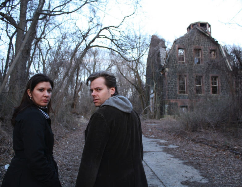 The filmmakers standing next to a creepy, abandoned house