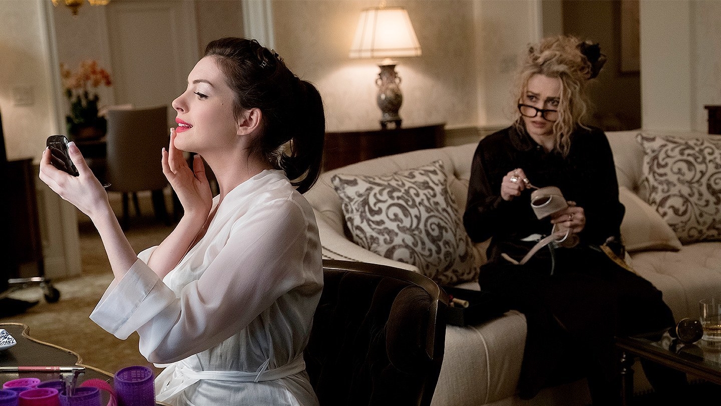 Anne Hathaway checks her mirror while Helena Bonham Carter sits on a couch