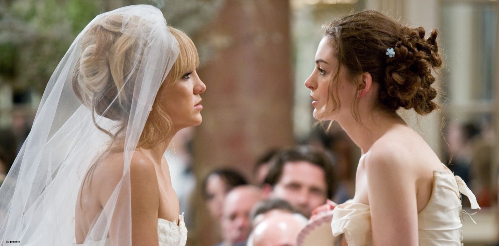 Kate Hudson and Anne Hathaway talk to each other in wedding dresses