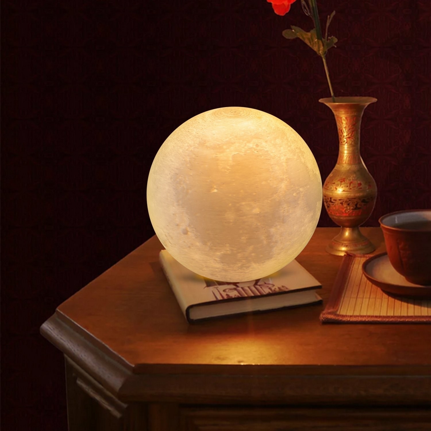A round lamp that looks like the moon is placed on a bedside table