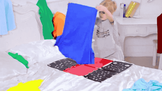 child uses plastic board to fold tee