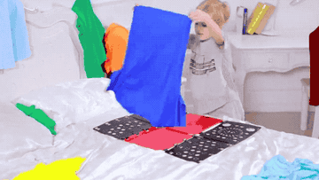child uses plastic board to fold tee