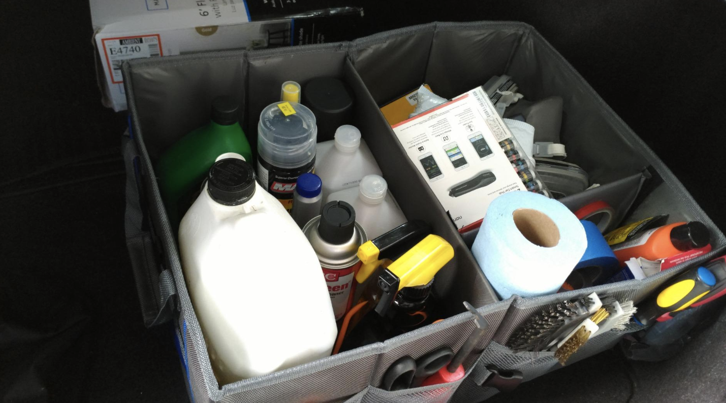 a canvas rectangular organizer with different square compartments in it full of different things in the trunk of someone&#x27;s car