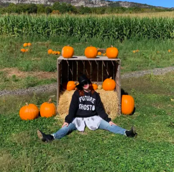 myself wearing the sweatshirt in a pumpkin patch