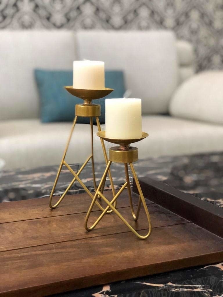 Two tripod candle holders with candles placed on them.