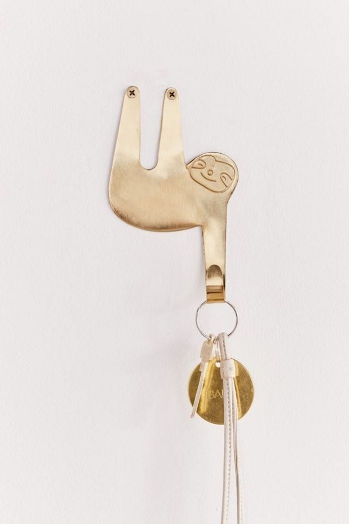 golden sloth hook with one of the sloth arms hanging down and holding a pair of keys
