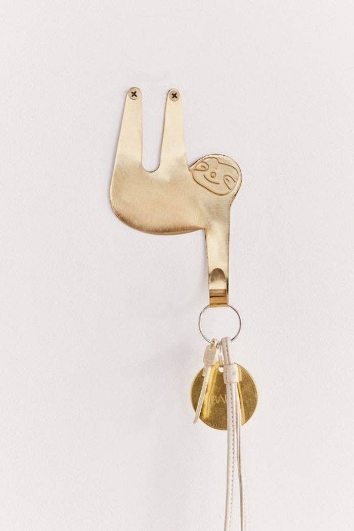 a golden sloth with one of its arms serving as the key &quot;hook&quot;