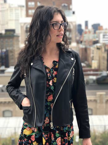 BuzzFeed editor wearing the moto-style jacket with a floral dress with a hand in one pocket