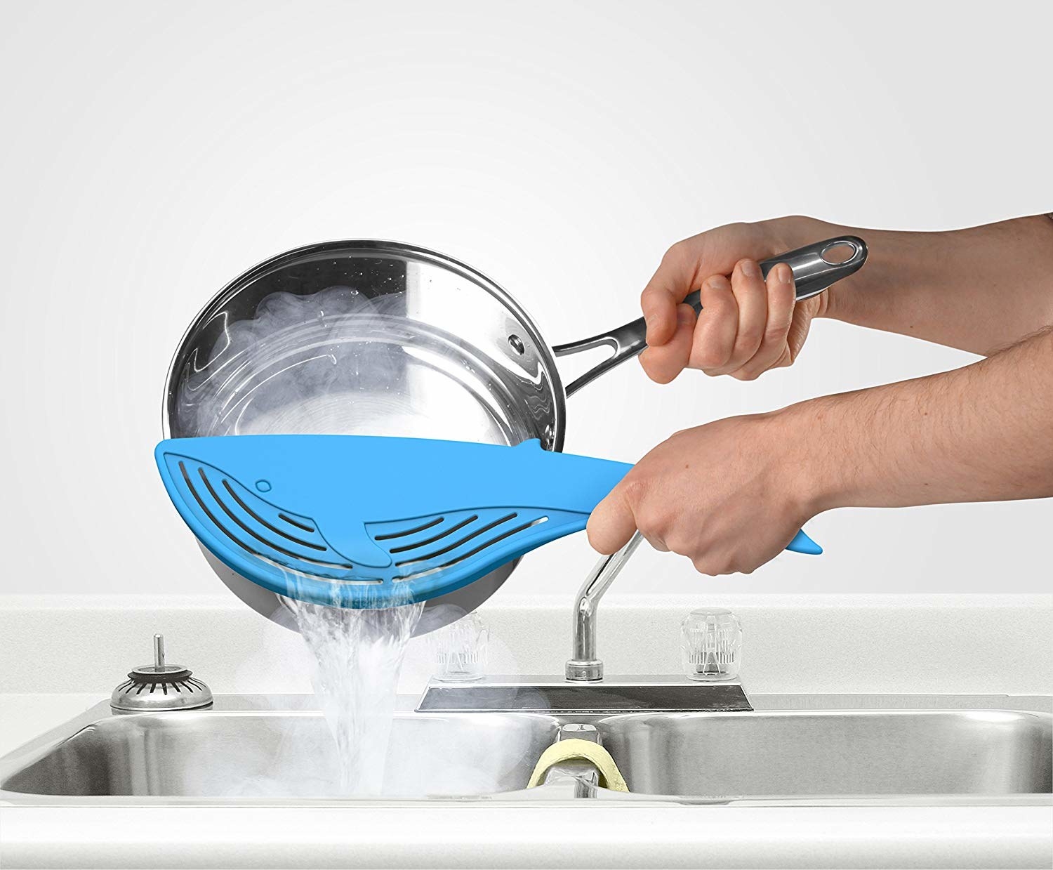A person straining water from a pot with the whale strainer