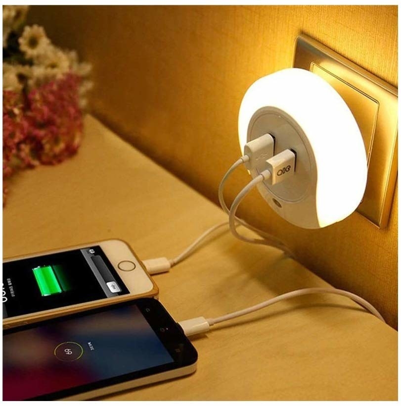 A night lamp plugged into a wall socket and two phones charging off it