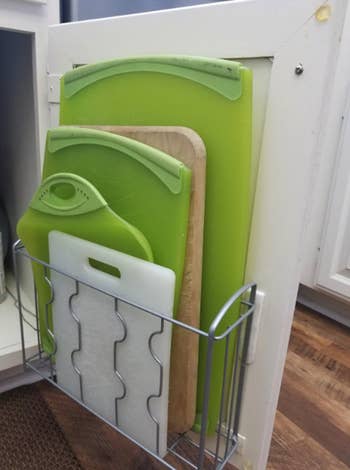 reviewer photo of them using the organizer for five cutting boards