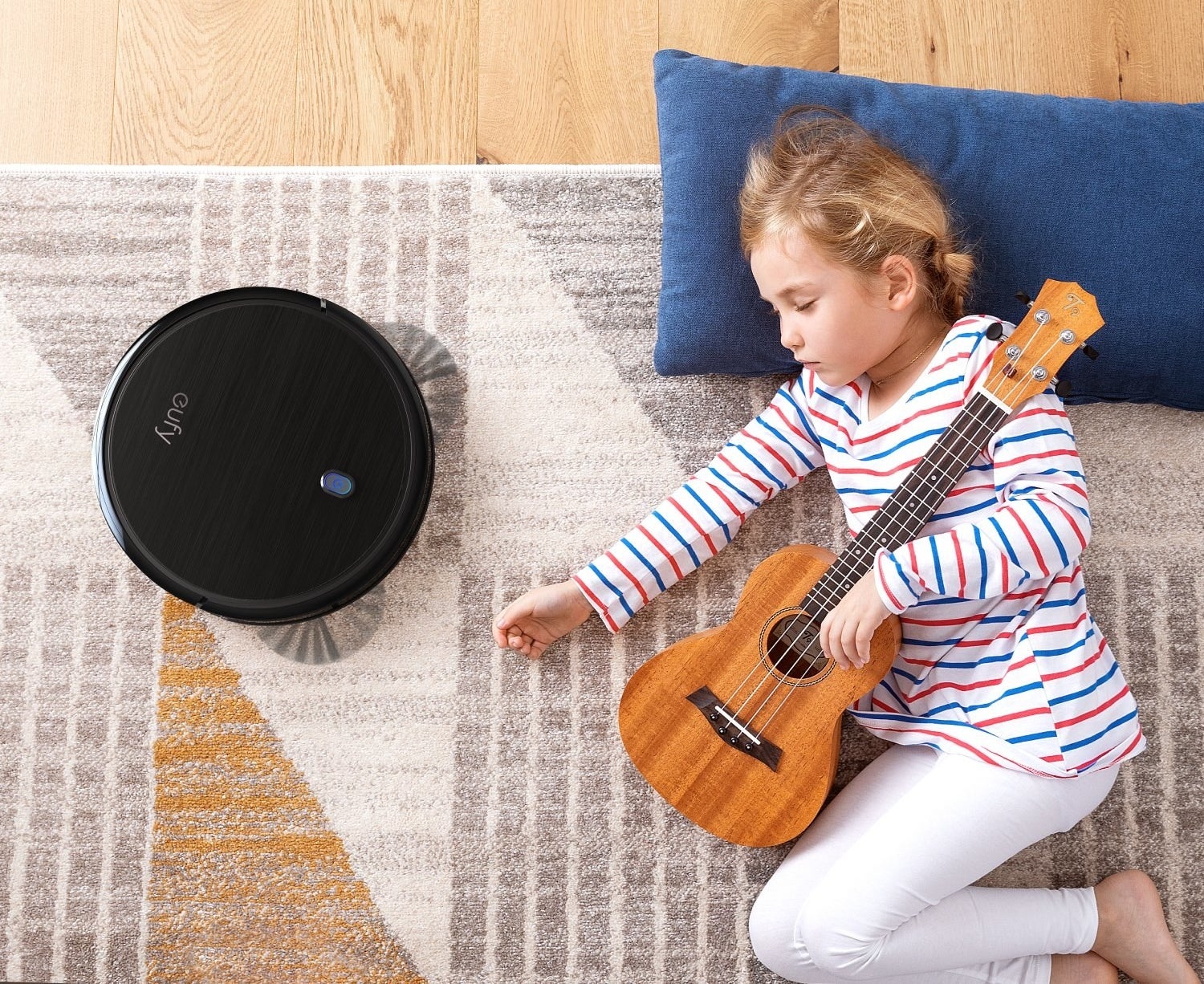 Young girl lying on ground with guitar next to robot vacuum 