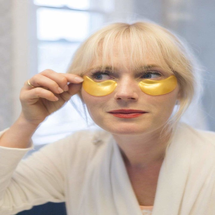 model applies gold eye masks to face