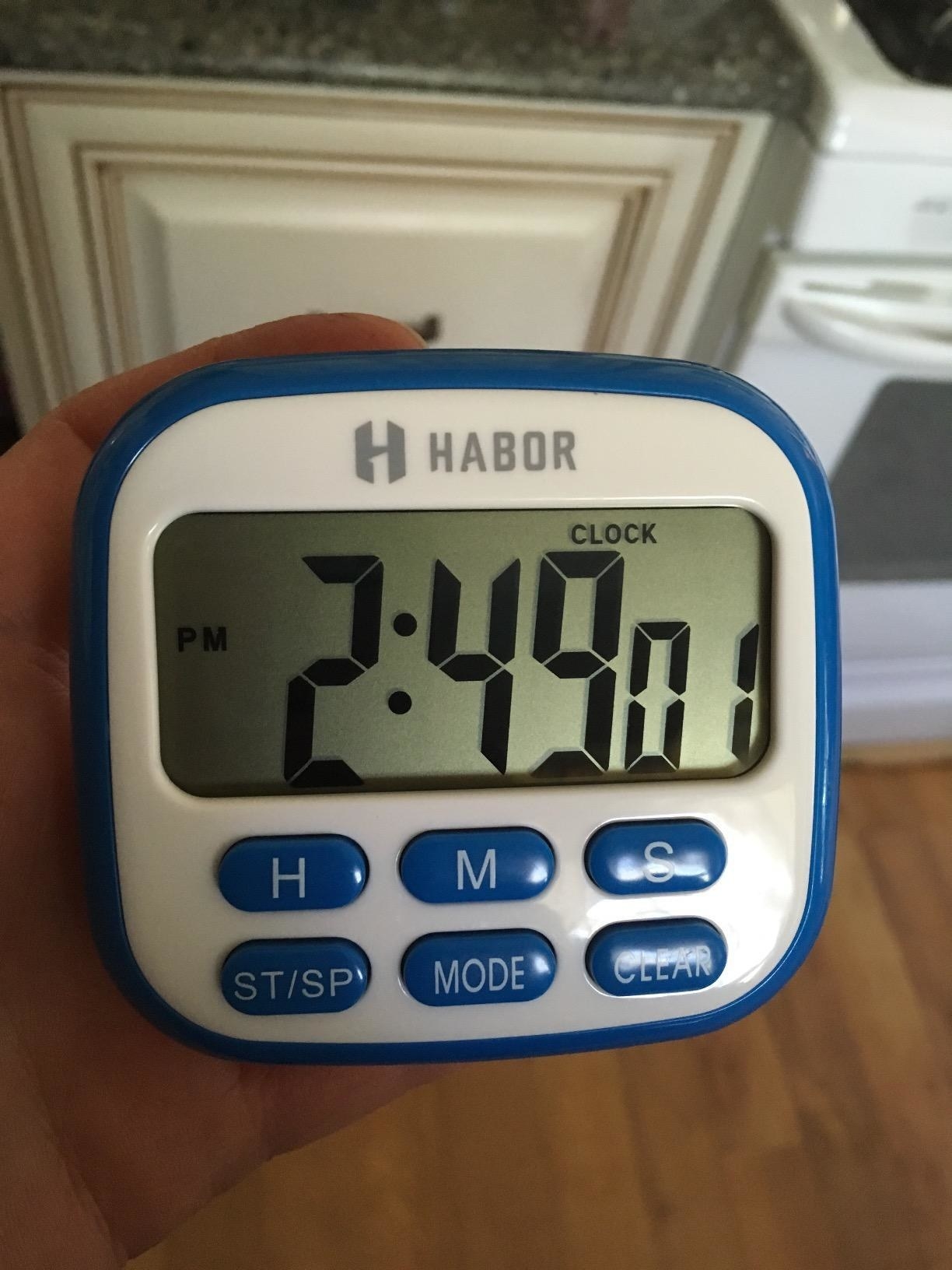 A reviewer holding the small digital timer